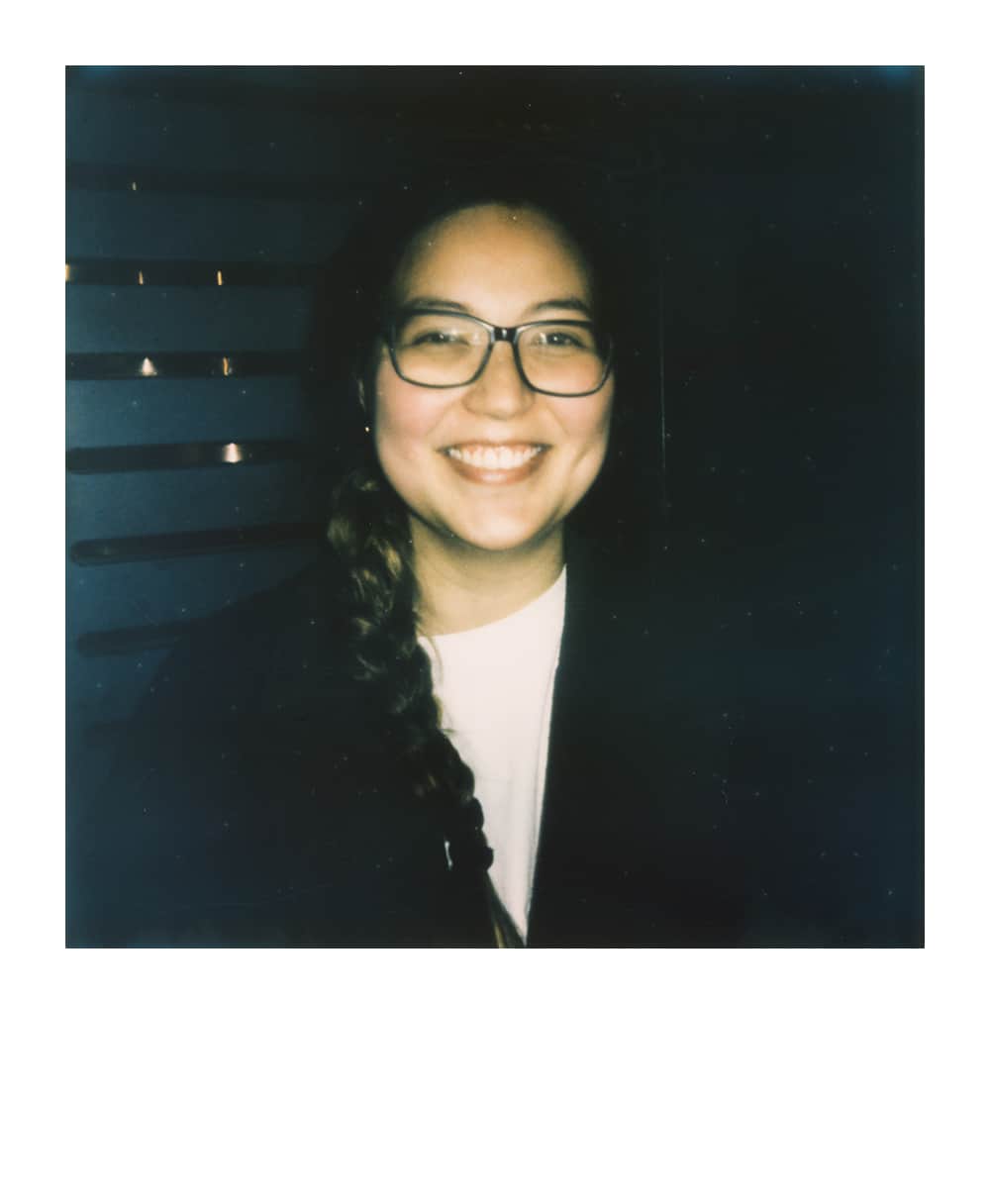 Leende kvinnlig Dungeon Master med glasögon och fläta i en Polaroid-stil porträtt